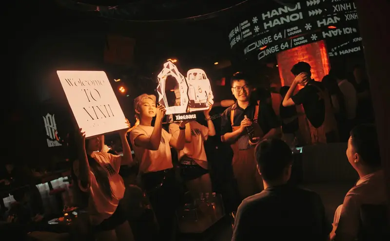 Đội ngũ Xính Lounge cầm bảng chào mừng khách tới bàn
